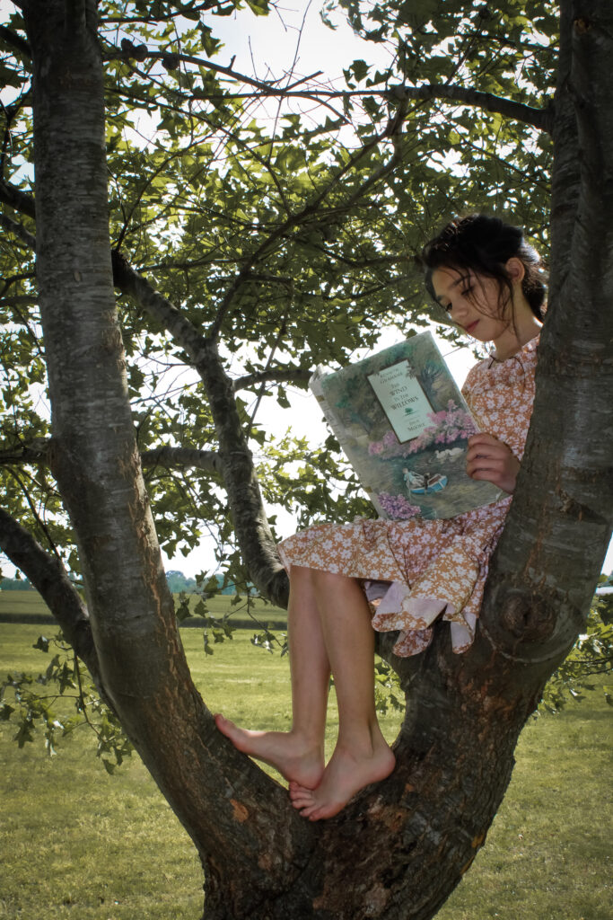 Girl reading a book in a tree.