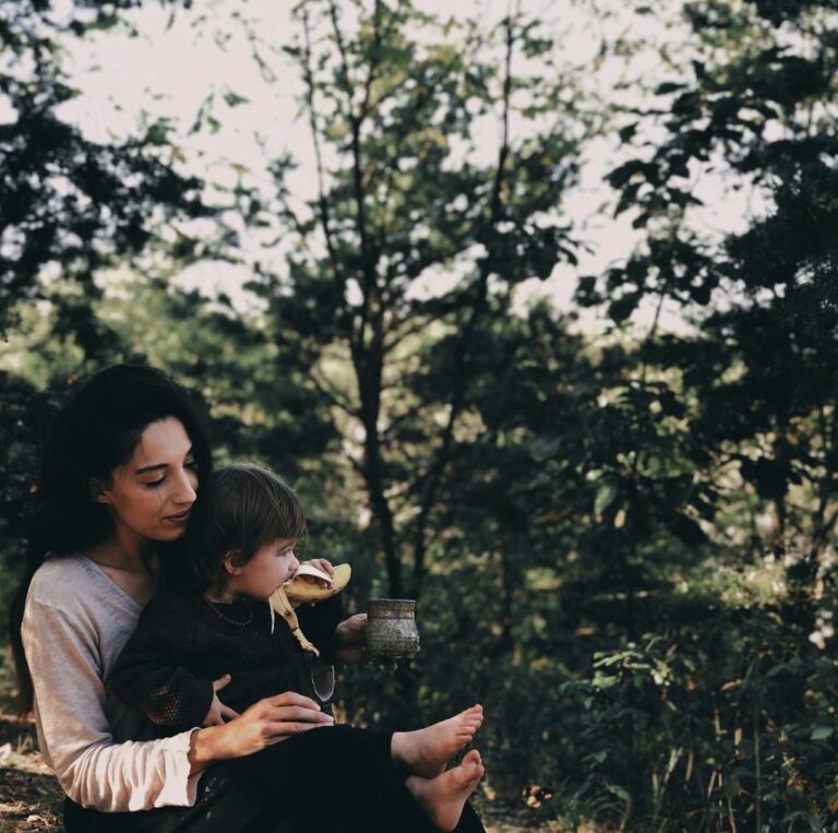 Mother holding a little girl on her lap in the woods